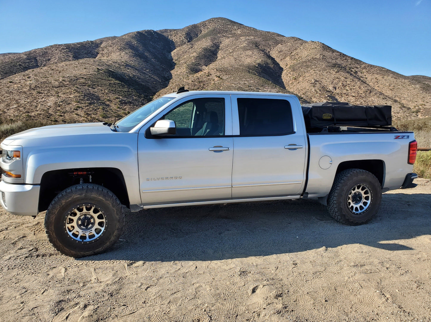Profile shot of a Silverado truck equipped with a Range Industries bed rack for 2014-2018 models, set against a scenic mountain landscape.