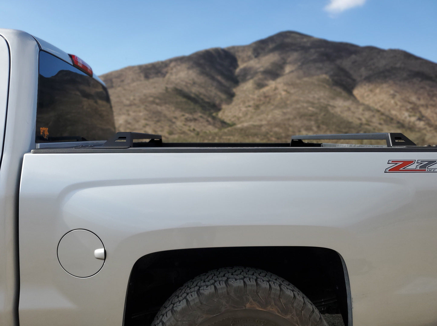 Side view of a 2014-2018 Silverado/Sierra 1500 truck featuring a Range Industries bed rack, displaying its compatibility with various truck models in an outdoor setting.