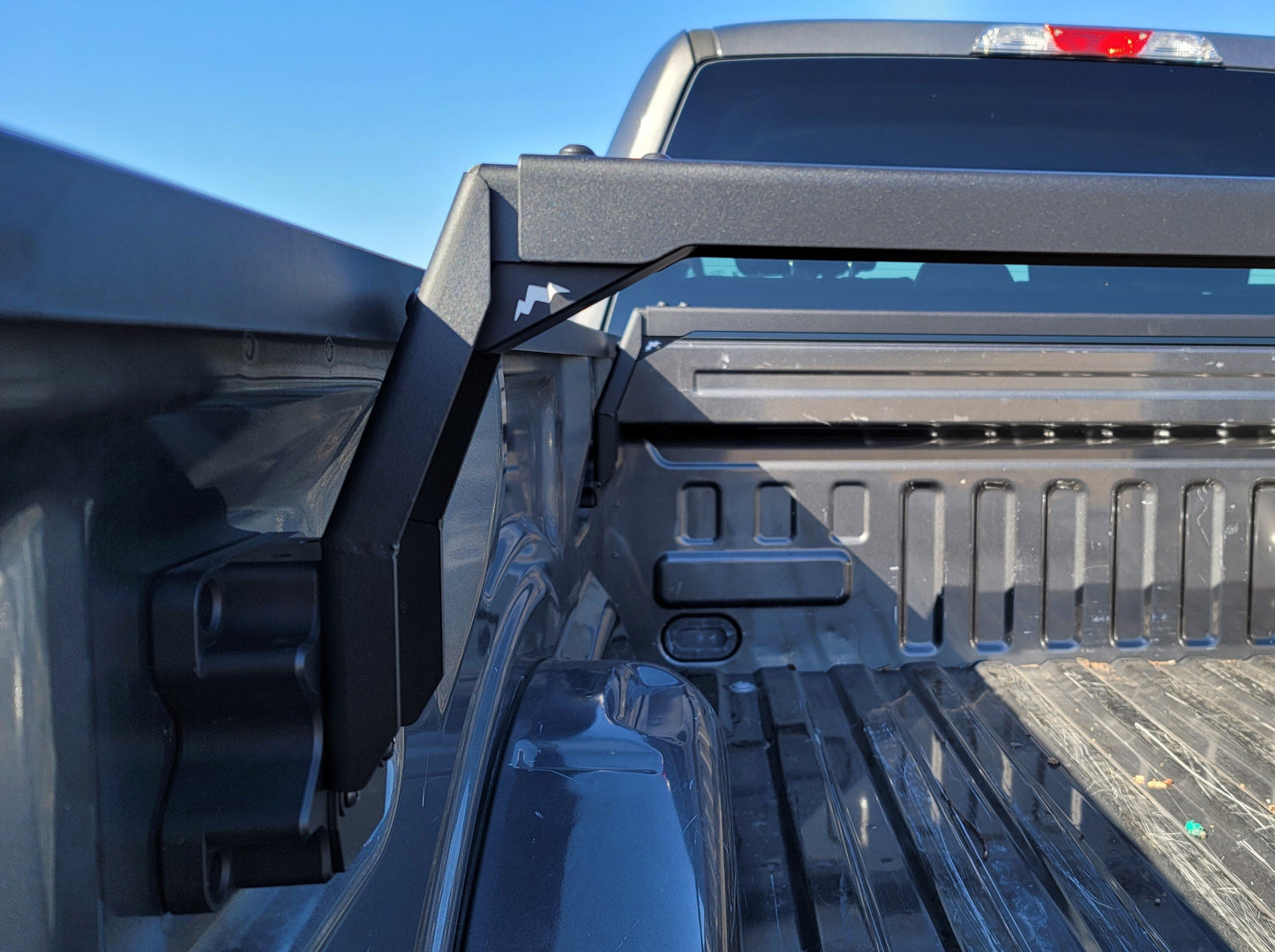 Side angle of the Range Industries 2015+ F-150 Low Profile Rooftop Tent Rack Kit installation, highlighting upright brackets and mount design in a truck bed.