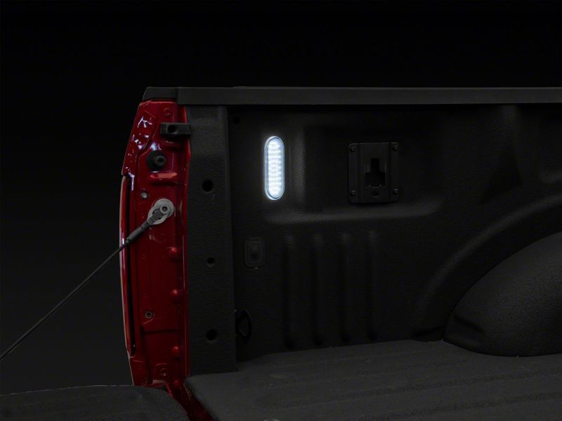 Raxiom Axial Series LED Cargo Light illuminated in a Ford truck bed, providing enhanced visibility for loading and unloading.