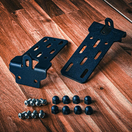 DirtBox Overland 270 Awning Mounting Bracket showing two black brackets and mounting hardware on a wooden surface, designed for roof top crossbars and camper canopies.