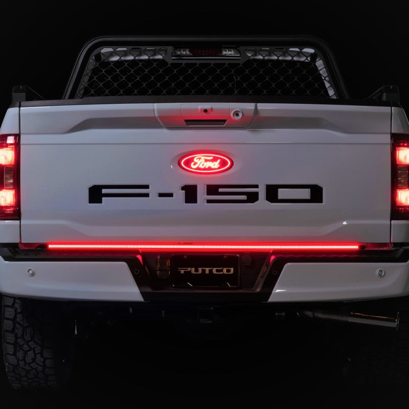 Putco 2021+ Ford F150 Freedom Blade 60in LED Tailgate Light Bar illuminated on a white Ford truck, showcasing red lighting and sleek design.
