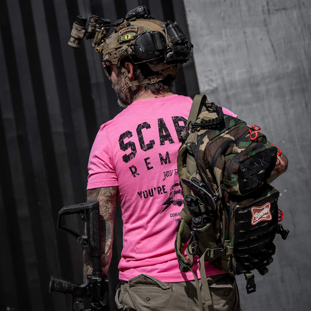 Side view of a man wearing a pink t-shirt featuring 'Scars Remind You That You're Alive' by Combat Iron Apparel.