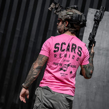 Load image into Gallery viewer, Tattooed man in a pink t-shirt saying 'Scars Remind You That You're Alive' by Combat Iron Apparel in an urban setting.