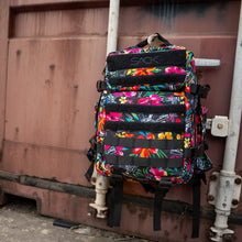 Load image into Gallery viewer, Combat Iron Apparel 25L Sack™ Original All-Day Molle Backpack with Pouch, resting against a grungy surface, showcasing its stylish floral look.