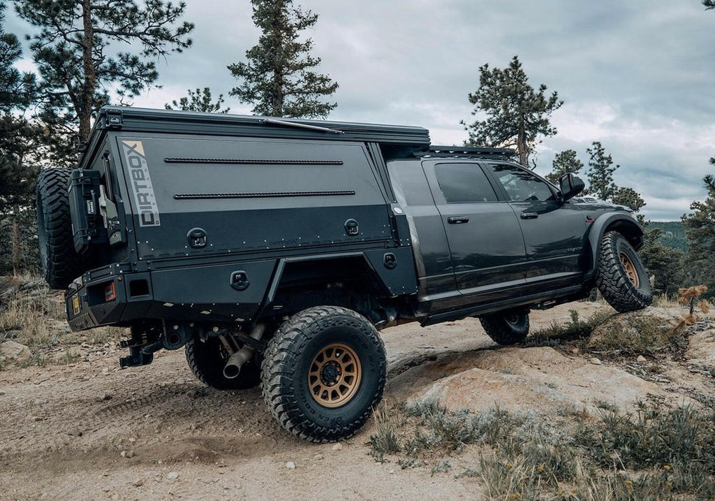 Dirtbox Overland Flatbed System Camper Box mounted on a truck, showcasing its rugged design and off-road capabilities on a rocky terrain.