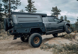 Dirtbox Overland Flatbed System Camper Box mounted on a truck, showcasing its rugged design and off-road capabilities on a rocky terrain.