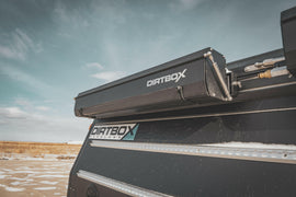 Dirtbox Overland Hard Case Shower/Bathroom Awning mounted on a vehicle, showcasing its sleek design against a cloudy sky.