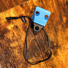 Load image into Gallery viewer, Blue Canopy Camper Rear Camera Relocation Mount by Dirtbox Overland with camera attached on a wooden background.