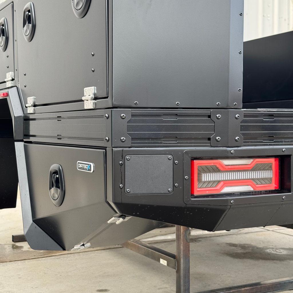 Close-up of the Transformer Drop Center Flatbed by Dirtbox Overland, showcasing a rugged, modular design with storage compartments and integrated taillights.
