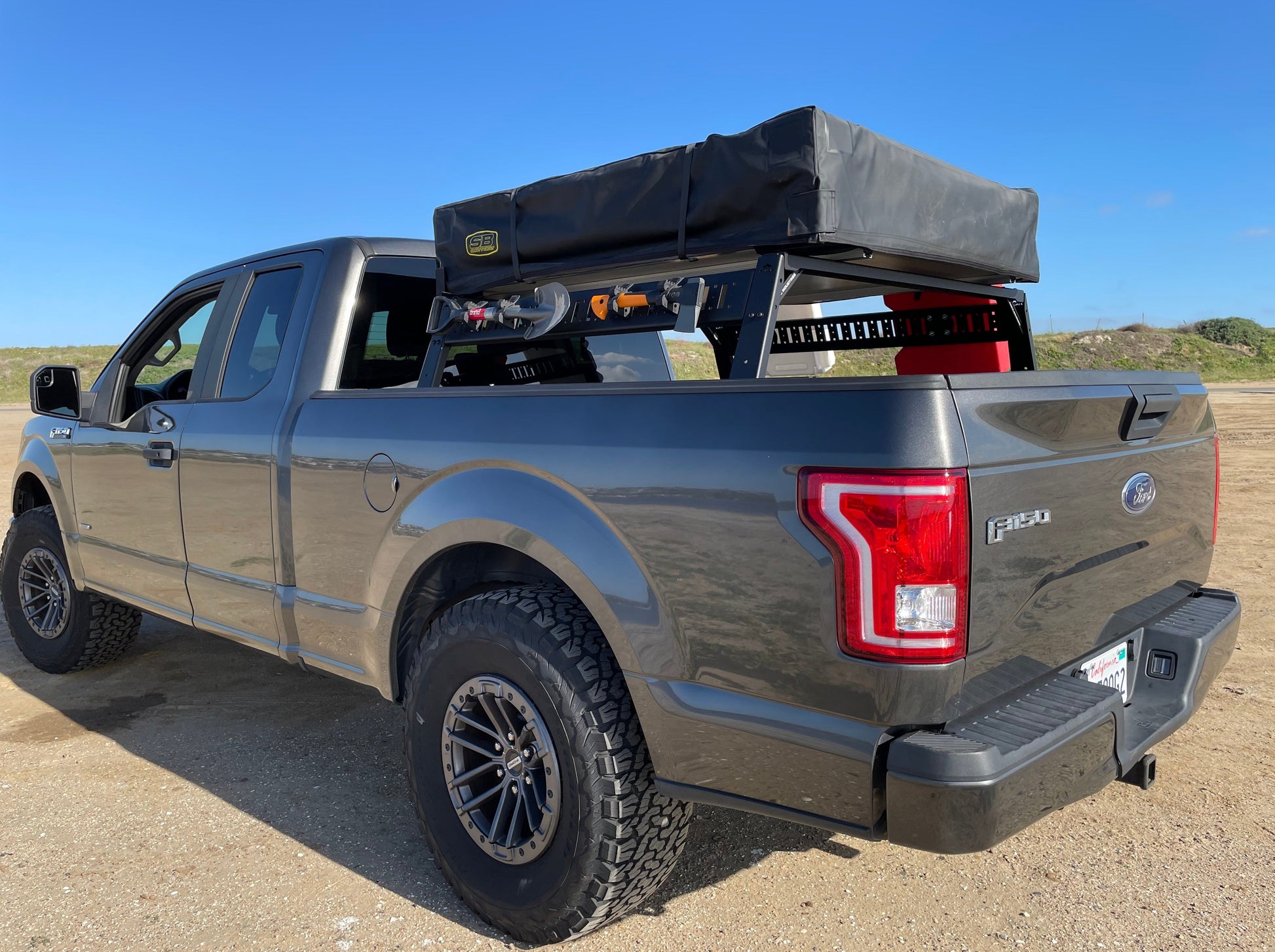 Close-up side view of the Range Industries 2015+ F-150 Mid Height Rooftop Tent Rack Kit on a Ford F-150, emphasizing the robust design and gear setup.