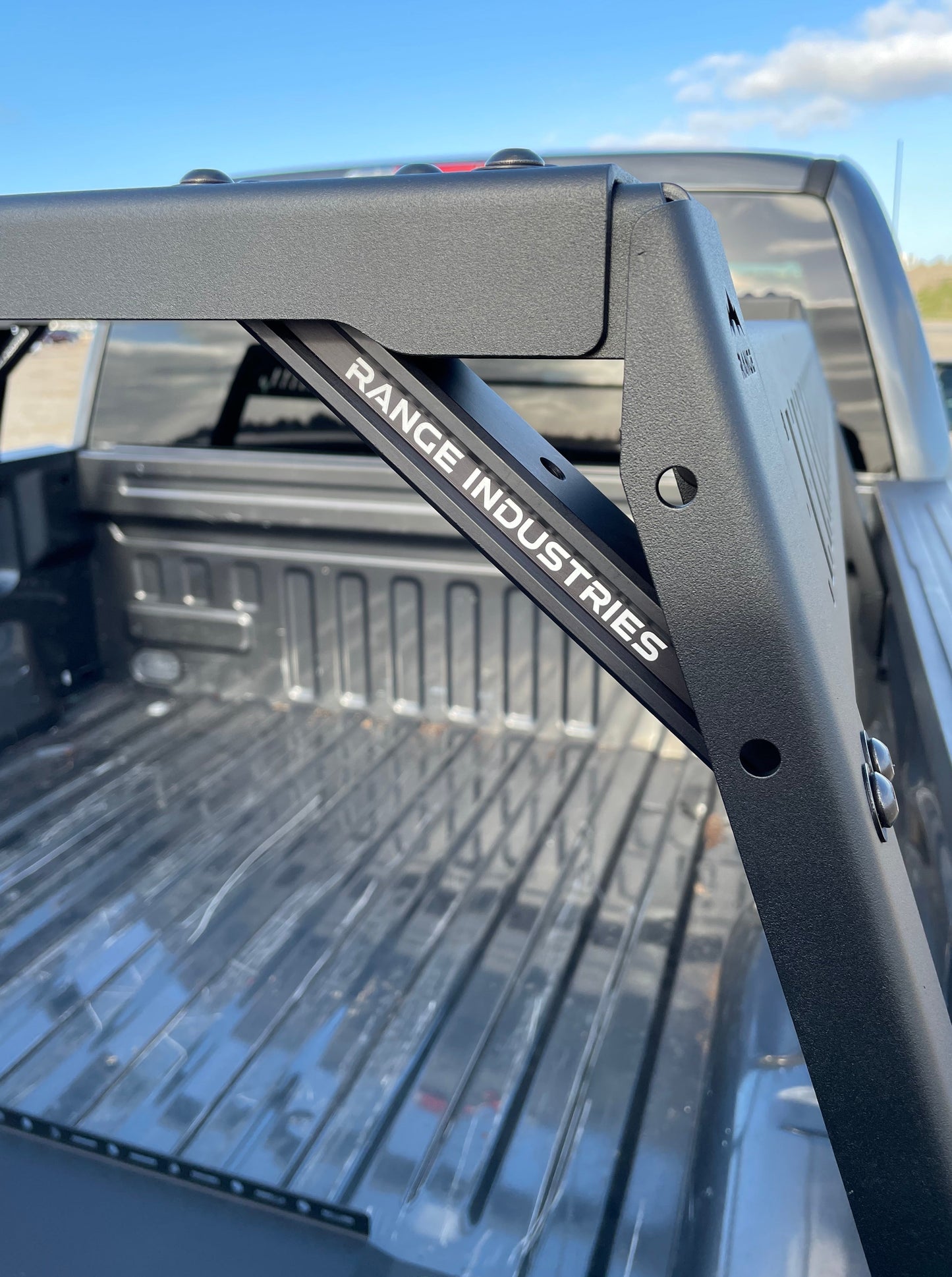 Detailed shot of the Range Industries F-150 Mid Height Rooftop Tent Rack Kit, focusing on the metal frame and branding, set inside a truck bed.