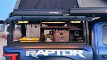 Load image into Gallery viewer, Dirtbox Overland Side Molle Box mounted in a truck, showcasing organized storage with lighting and gear inside.
