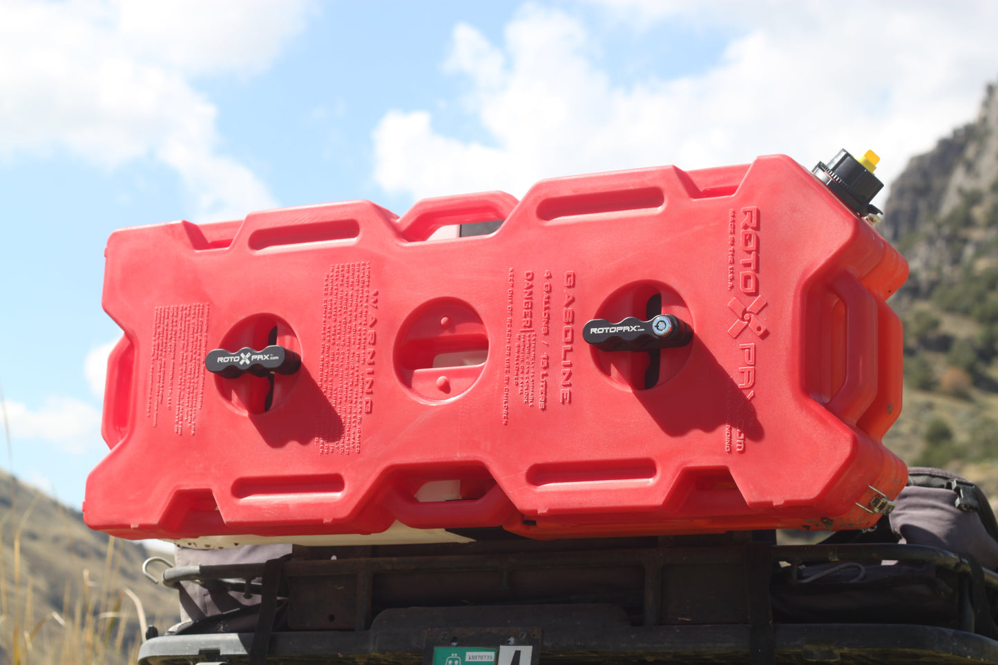 4 Gallon Gasoline container by RotopaX positioned on a vehicle roof, set against a scenic outdoor backdrop, perfect for off-road enthusiasts.
