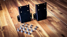 Load image into Gallery viewer, Dirtbox Overland 270 Awning High Mount Bracket kit featuring two black metal brackets and assorted bolts and nuts on a wooden surface, designed for enhanced clearance in outdoor setups.
