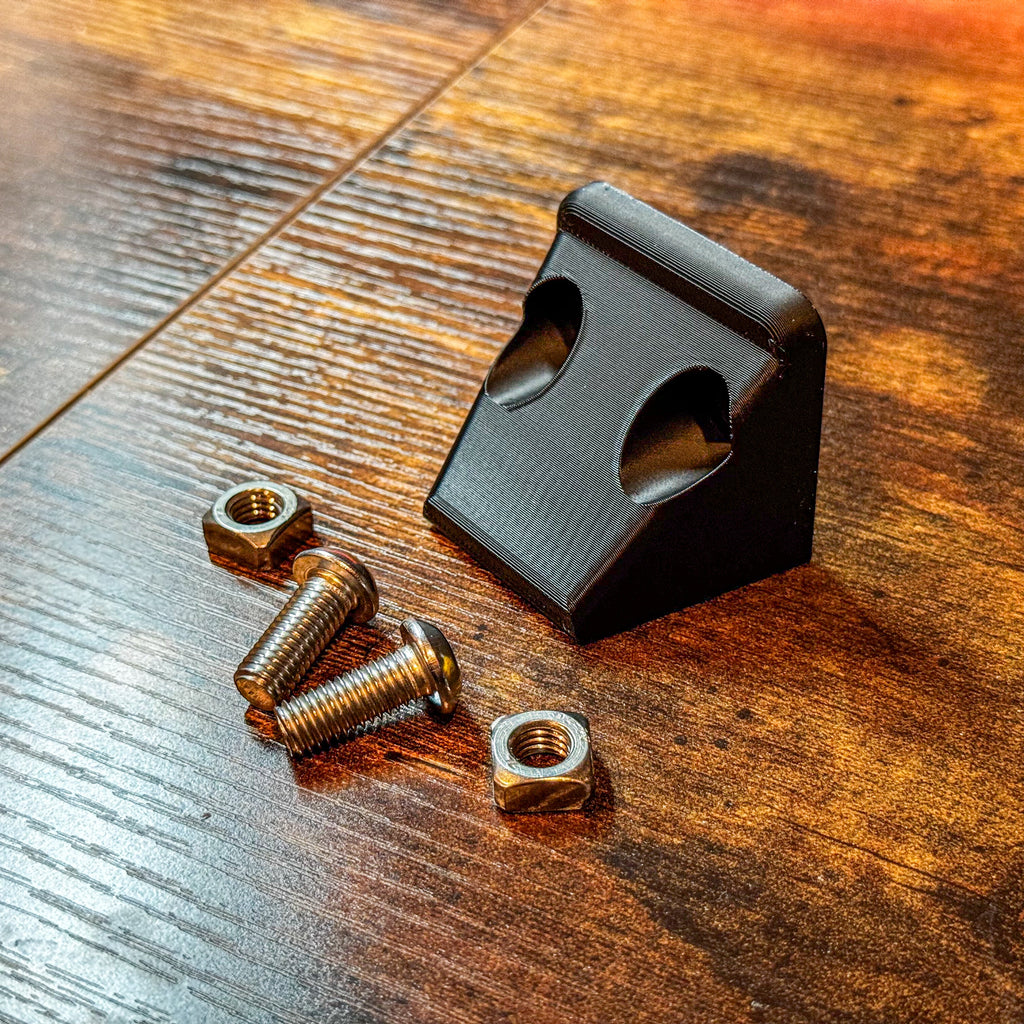 Canopy Camper Rear Camera Relocation Mount by Dirtbox Overland with metal screws and nuts on a wooden surface.