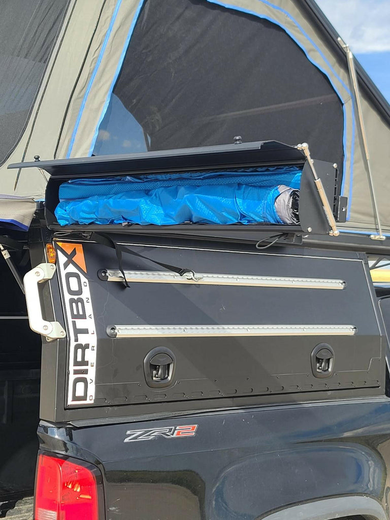 Hard case shower awning from the Ultimate Camp Shower Set by Dirtbox Overland, rolled up in the storage compartment of a truck.