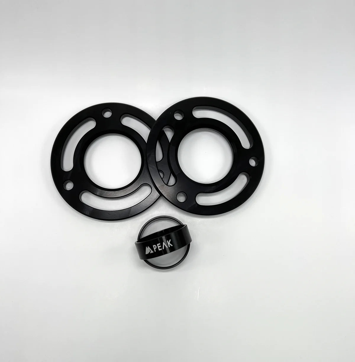 Components of the PEAK SUSPENSION 2 Piece Lift Kit for Silverado ZR2 and Sierra AT4X, including top mount and lower spring perch spacers in a stylish black design.