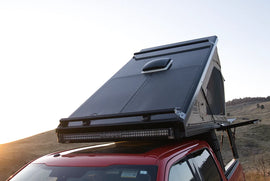 120w Ultra Light Solar Panel mounted on the roof of a red truck, showcasing its sleek design for outdoor adventures by Lone Peak Camper and Accessories.