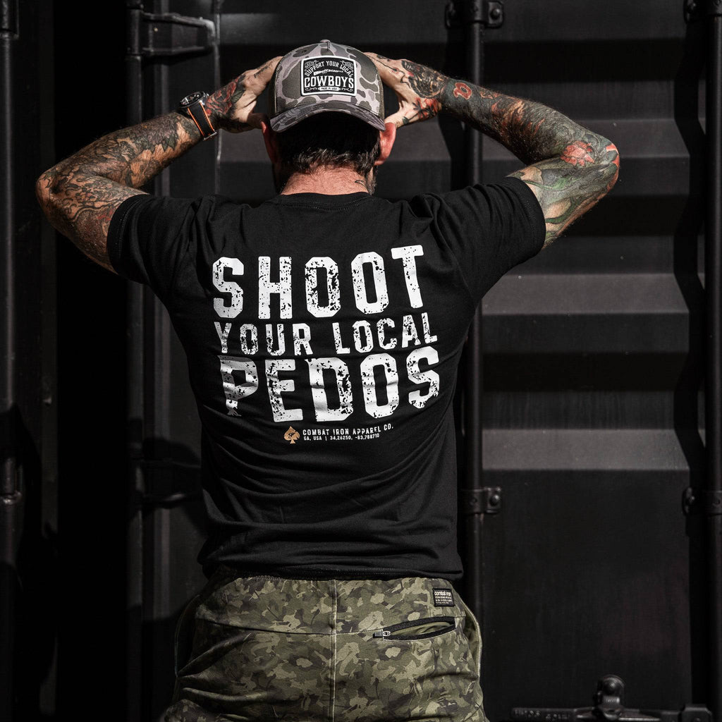 A man from behind wearing a black t-shirt that reads 'Shoot Your Local Pedos' on the back, designed by Combat Iron Apparel.