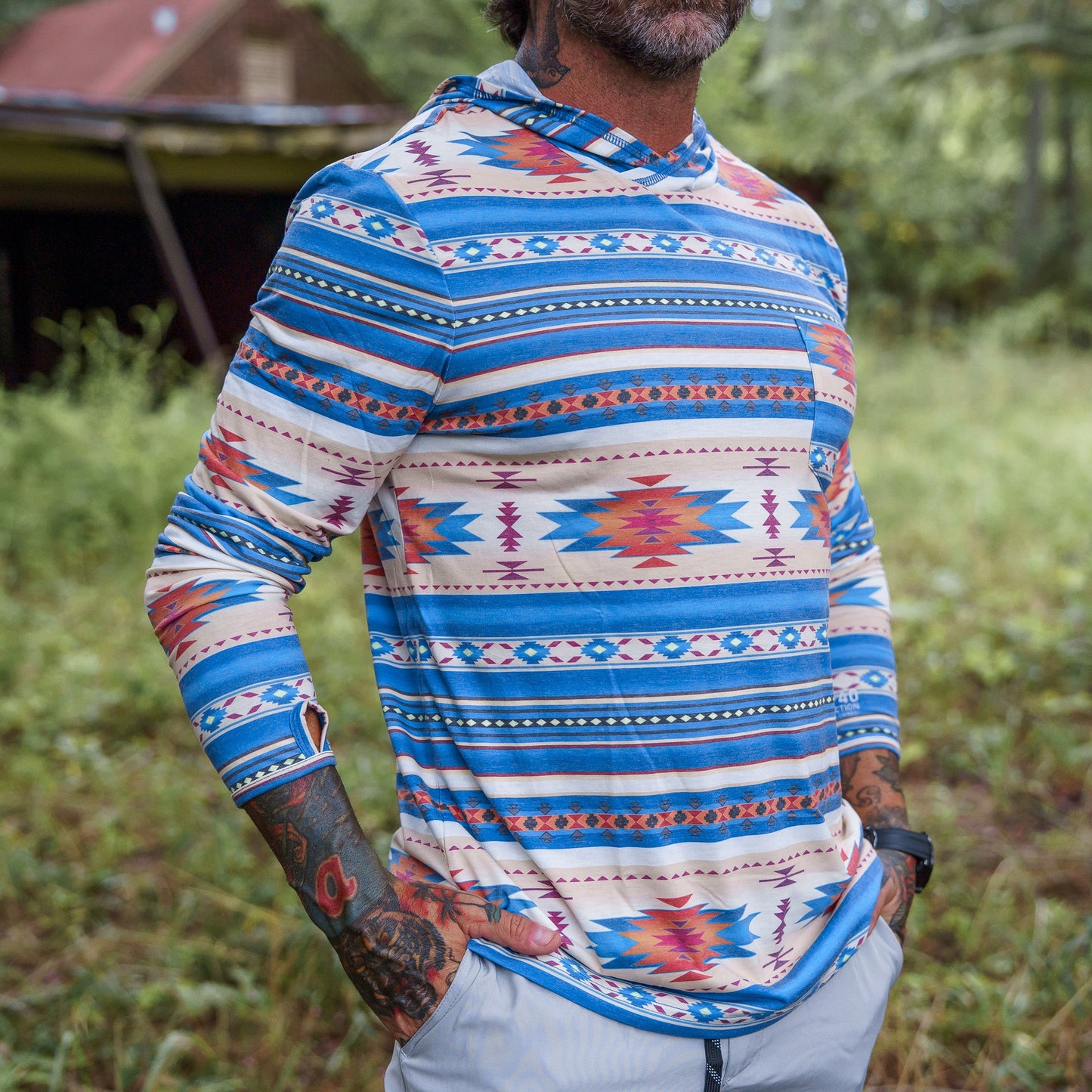 Men's Outdoors Long Sleeve Performance Hoodie by Combat Iron Apparel, styled outdoors with vibrant tribal patterns.