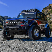 Load image into Gallery viewer, Dynamic shot of a Ford Bronco showcasing the Superwinch 21-24 Hidden Winch Mount, ideal for off-road adventures in challenging landscapes.
