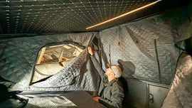 A user adjusting the insulation walls inside the Canopy Camper Tent equipped with the Dirtbox Overland Insulation Kit, designed for all-weather comfort.