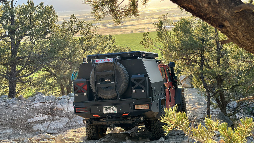 The back view of a Dirtbox Overland Flatbed System Full Box navigating a rocky path, demonstrating its functional design for outdoor exploration.