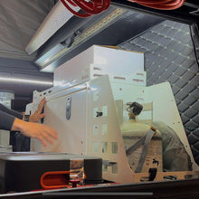 Load image into Gallery viewer, Dirtbox Overland Front Storage Box shown in an outdoor camper setup with a propane tank and gear organized, perfect for adventure enthusiasts.