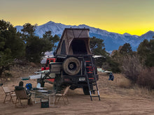 Load image into Gallery viewer, Scenic campsite featuring a Dirtbox Overland Flatbed System Full Box with an elevated tent setup, surrounded by stunning mountain views during sunset.