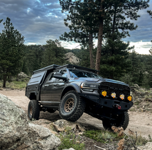 Load image into Gallery viewer, Dirtbox Overland Flatbed System Full Box on a black truck navigating rocky terrain, demonstrating its off-road capabilities.