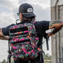 Load image into Gallery viewer, Combat Iron Apparel 25L Sack™ Original All-Day Molle Backpack with Pouch placed upright, highlighting its colorful design.