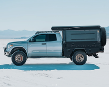 Load image into Gallery viewer, Silver truck with Dirtbox Overland Flatbed System Full Box parked on a salt flat, demonstrating its versatility and off-road capabilities.