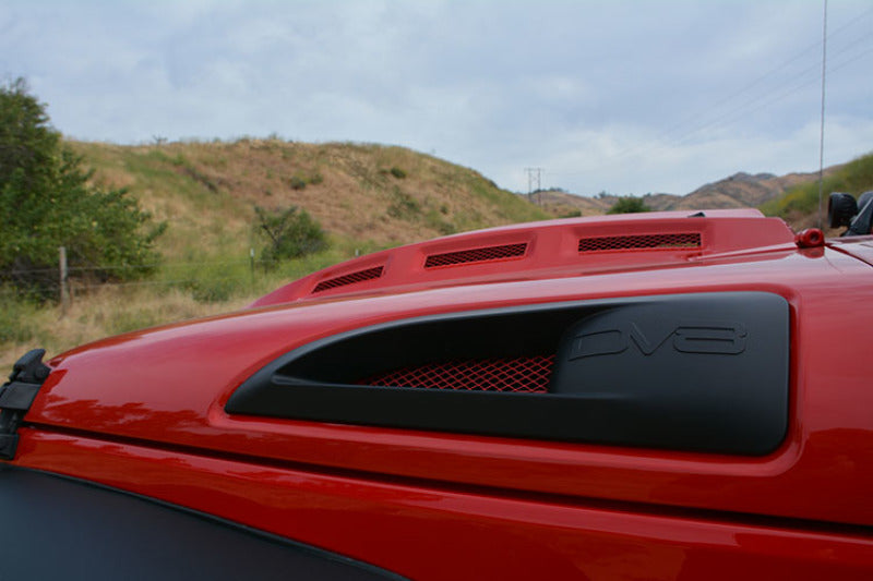 Front view of a red Jeep Wrangler JK featuring DV8 Offroad Metal Heat Dispersion Hood and off-road lights.
