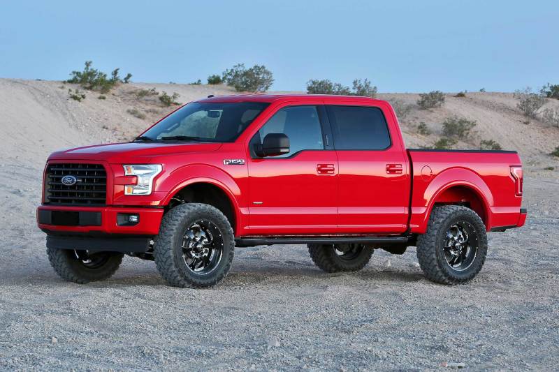 Upgraded red 2015-2020 Ford F-150 2WD with Fabtech 4-inch Performance System, equipped for off-road adventures with lifted suspension and robust tires.